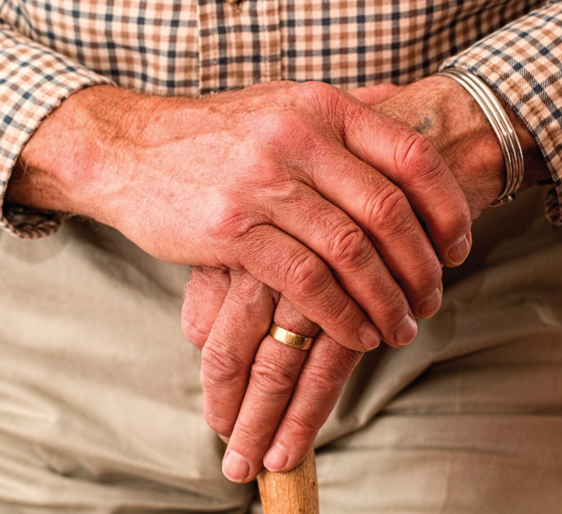 An older gentleman's hands resting on his walking cane